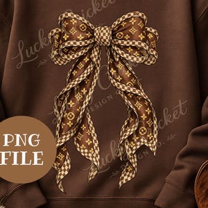 Könnte beinhalten: Ein braunes Sweatshirt mit einem großen Schleifendesign. Die Schleife ist braun und beige mit einem sich wiederholenden Logomuster und karierten Akzenten. Die Worte "PNG FILE" befinden sich in einem braunen Kreis.