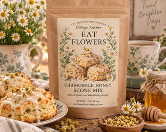 May include: A brown paper pouch of The Flower Food Company Cottage Kitchen Eat Flowers Chamomile Honey Scone Mix. The label features illustrations of chamomile flowers and scones, with text stating Net Wt. 16 oz (454 g) and the website address.