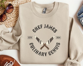 May include: Beige sweatshirt with a black graphic design that says "Chef James Culinary Genius" with crossed knives and the text "Estd 2024".