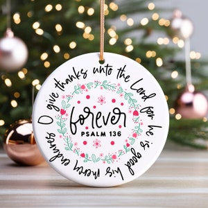 May include: White round Christmas ornament with a floral wreath design and the text "O give thanks unto the Lord for he is good & his mercy endures forever. Psalm 136."