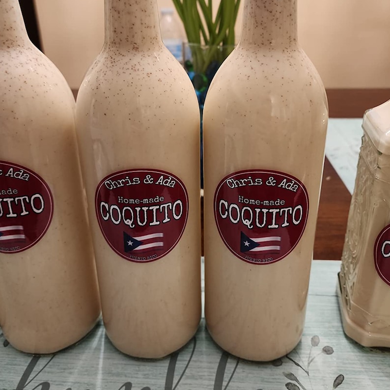 Pode incluir: Tr&ecirc;s garrafas de vidro cheias de um l&iacute;quido branco e etiquetadas "Chris & Ada Coquito caseiro" com um c&iacute;rculo vermelho e uma bandeira porto-riquenha.