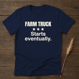 Puede incluir: Camiseta azul marino con el texto blanco "FARM TRUCK Starts eventually." La camiseta tiene cuello redondo y mangas cortas. Una espiga de trigo es visible en el lado derecho de la camiseta.