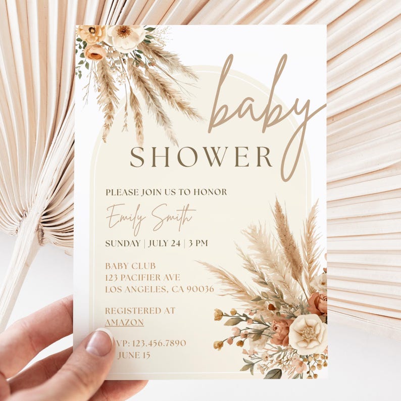 May include: Baby shower invitation with floral and pampas grass accents. The invitation features the words "baby shower" in a script font, along with details for the event, including the honoree's name, date, time, and location.