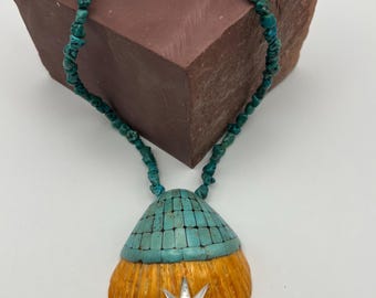 Puede incluir: Un collar con un colgante de concha turquesa y naranja con un diseño de estrella de plata. El collar está hecho de cuentas de turquesa y tiene un cierre de plata.