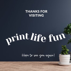 Pu&ograve; includere: Un muro blu scuro con il testo "THANKS FOR VISITING print life fun Hope to see you again!" in bianco. Due piante in vaso sono in primo piano, una con un vaso bianco e l'altra con un vaso grigio.