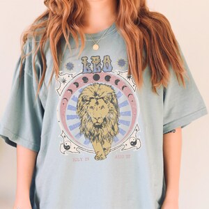 May include: A light blue t-shirt with a graphic print of a lion with the text "LEO" and dates "JULY 23 - AUG 22".
