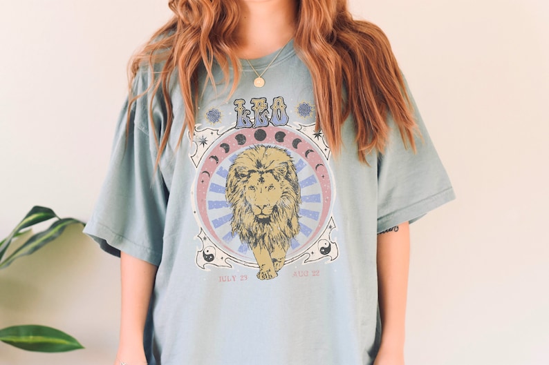 May include: A light blue t-shirt with a graphic print of a lion with the text "LEO" and dates "JULY 23 - AUG 22".