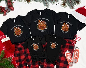 May include: A set of black t-shirts with a gingerbread house graphic and the text "Gingerbread Baking Crew" and "Miller Bakery". The shirts are arranged on a red and black plaid background with a Santa hat and candy canes.