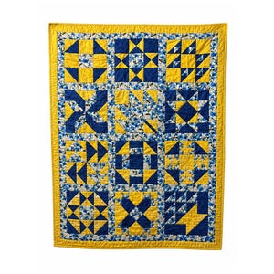 Può includere: Una trapunta fatta a mano con un design patchwork. La trapunta presenta un motivo ripetuto di forme geometriche blu e gialle, incorniciato da un bordo giallo. La trapunta è probabilmente realizzata in tessuto di cotone.