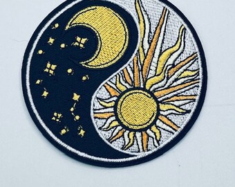 Può includere: Un simbolo yin yang nero e bianco con una luna crescente e un sole gialli. La luna è circondata da piccole stelle e il sole ha raggi di luce. La toppa è ricamata.