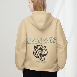 May include: A beige hooded sweatshirt with a black and white jaguar graphic and the text "JAGUARS EST 1996" on the back.