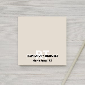 May include: A white business card with black text that reads "RT Respiratory Therapist Maria Jones, RT". The card is on a light wood surface with a white pencil beside it.