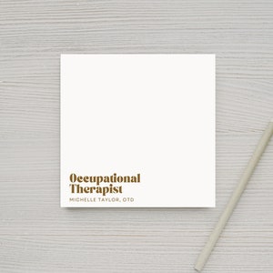 Peut inclure: Une carte blanche avec le texte "Occupational Therapist" en lettres brunes et le nom "Michelle Taylor, OTD" en lettres brunes plus petites en dessous.