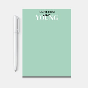Peut inclure: Un bloc-notes vert clair avec le texte "A note from mr YOUNG" en haut. Un stylo blanc est à côté du bloc-notes.