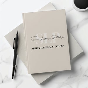 May include: A beige notebook with the text "SLP Speech Language Pathology" and "ASHLEY HANES, M.S., CCC-SLP" printed on the cover.