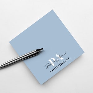 May include: A light blue square note pad with the text "PA Physician Assistant KAYLEE KLINE, PA-C" in black and white lettering.