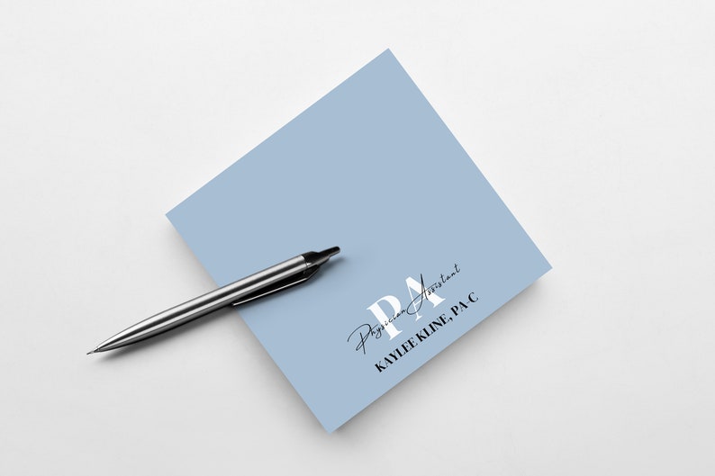 May include: A light blue square note pad with the text "PA Physician Assistant KAYLEE KLINE, PA-C" in black and white lettering.