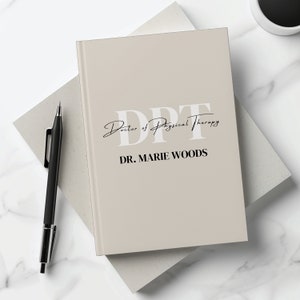 May include: A beige notebook with the text "DPT Doctor of Physical Therapy" and "DR. MARIE WOODS" in black text.