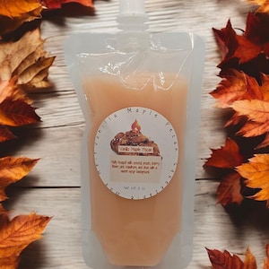 Könnte beinhalten: Ein durchsichtiger Plastikbeutel gefüllt mit einer hellorangen Duftkerze. Das Etikett lautet "Vanilla Maple Pecan" und beschreibt den Duft als "Nussig, geröstet mit süßem Pfirsich, Kirsche, Birne, rosa Weißdorn und dem mit einem süßen Sirup-Hintergrund". Das Etikett gibt auch "Nettogewicht 8 oz" an.