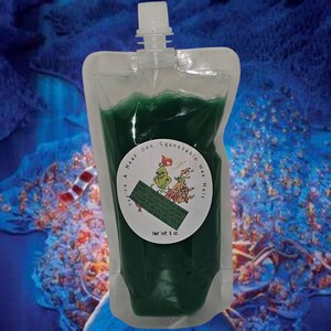 May include: A green squeeze bottle of wax melt with a white label that says "You're a Mean One, Squeezable Wax Melt, Net Wt. 8 oz."