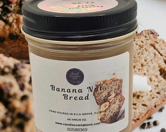 May include: A glass jar candle with a brown label that reads "Banana Nut Bread". The label also includes the text "Hand poured in Ells Grove, Illinois", "48 hrs/8 oz", "www.candlescentations.com", and "60588369".