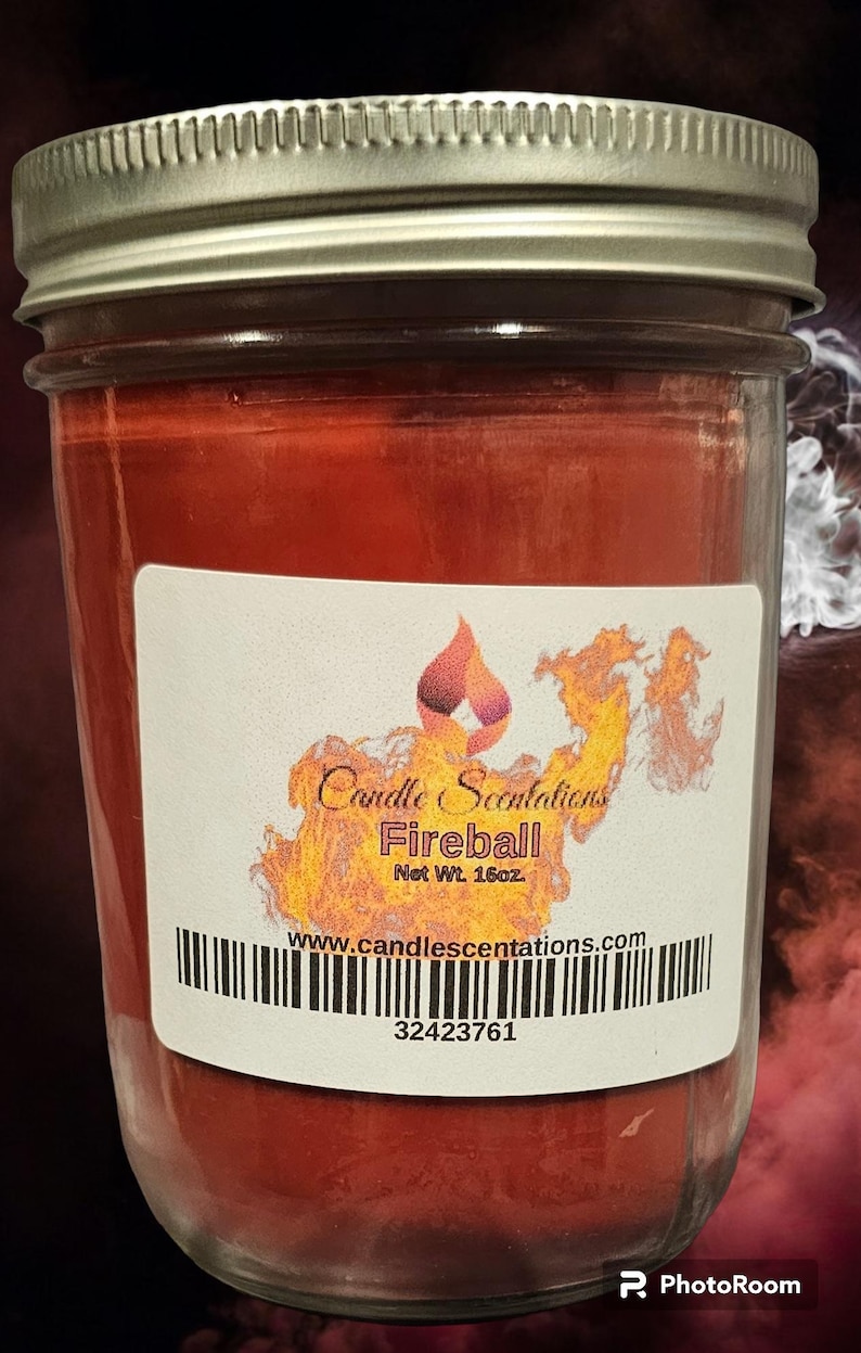 Pu&ograve; includere: Una candela rossa in un barattolo di vetro con un'etichetta bianca che recita "Candle Scentations Fireball Net Wt. 16oz. www.candlescentations.com 32423761".