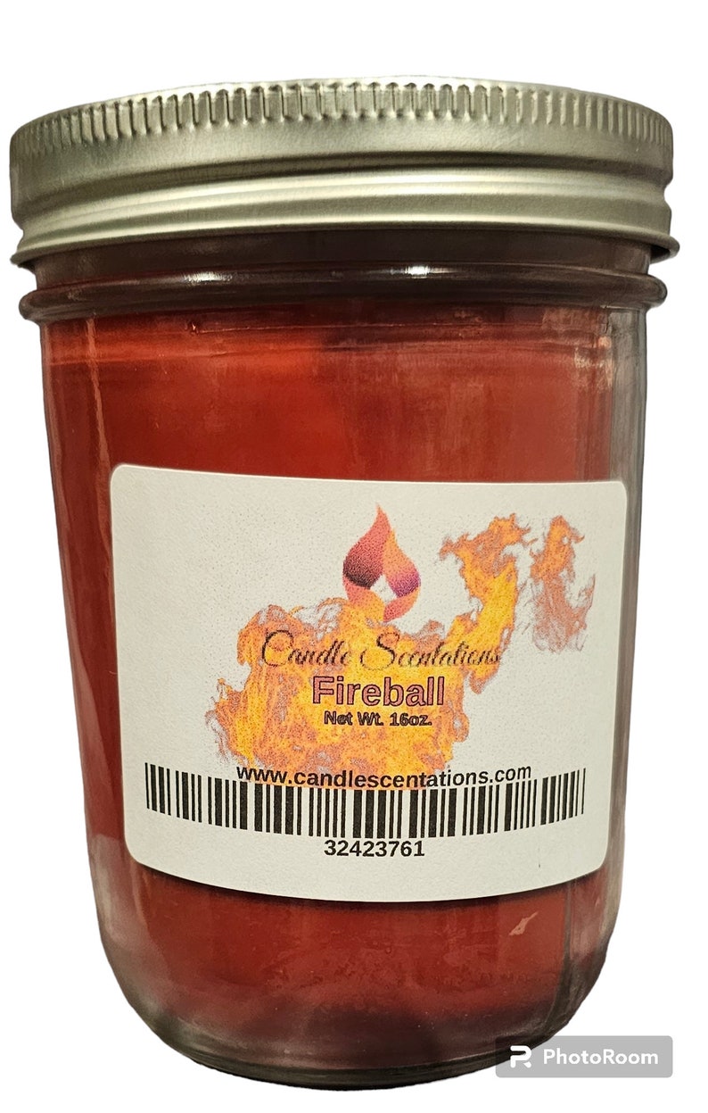 Pu&ograve; includere: Una candela rossa in un barattolo di vetro con un'etichetta bianca che recita "Candle Scentations Fireball Net Wt. 16oz www.candlescentations.com 32423761".