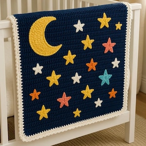 Op de afbeelding: Een marineblauwe gehaakte babydeken met een gele halve maan en diverse gekleurde sterren. De deken heeft een witte, geschulpte rand en is over een wit ledikant gedrapeerd.