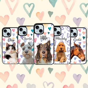 May include: Five personalized phone cases with different pet portraits. Each case features a white background with a purple, pink, and blue watercolor heart pattern. The cases are labeled with the names "Chip", "Charlie", "Uffe", "Murphy", and "Cookie".