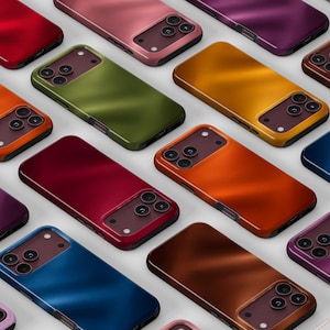 May include: A collection of smartphone cases in various solid colors including red, olive green, orange, yellow, blue, and purple. Each case features a rectangular camera cutout with three circular lens openings and a smooth, satin-like finish.