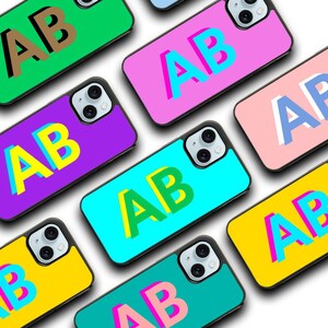 May include: Assortment of phone cases with the letters "AB" in various colors and styles. The cases are all black and have a clear back.