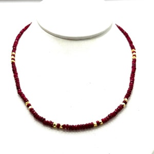 May include: A red gemstone necklace with gold accents. The necklace is made of small, round beads and is approximately 18 inches long.