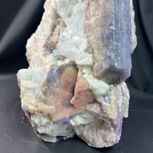 Könnte beinhalten: Ein Cluster aus rosa, violetten und weißen Kristallen mit einem silbrigen Schimmer. Die Kristalle sind in einer groben, natürlichen Formation angeordnet. Eine US-Viertel-Dollar-Münze ist zur Größenbestimmung enthalten.