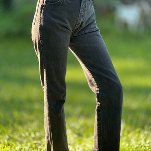 May include: A pair of black denim jeans with a frayed hem. The jeans are fitted through the leg and have a high waist.