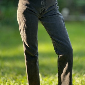 May include: Black denim jeans with a frayed hem.