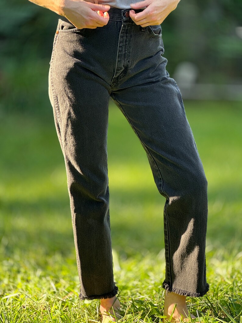 May include: Black denim jeans with a frayed hem.