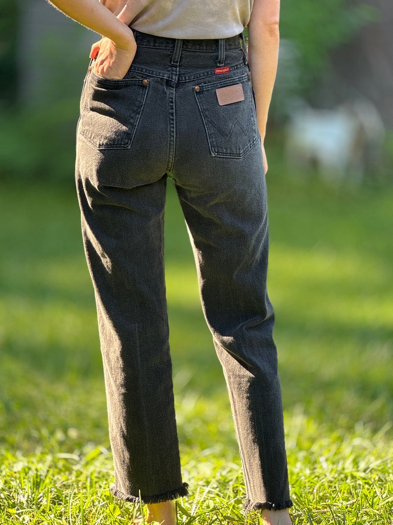 May include: A pair of dark gray denim jeans with a frayed hem. The jeans have a high waist and a straight leg.