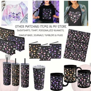 Pu&ograve; includere: Una collezione di prodotti a tema Halloween con un motivo bianco e nero con accenti viola, rosa e arancioni. Il motivo include varie icone di Halloween come fantasmi, pipistrelli, zucche e mais caramellato. I prodotti includono una t-shirt, una felpa, una trousse da trucco, un diario, un bicchiere e una tazza.