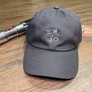 May include: A dark gray baseball cap with a white embroidered logo that says "EN + JO".