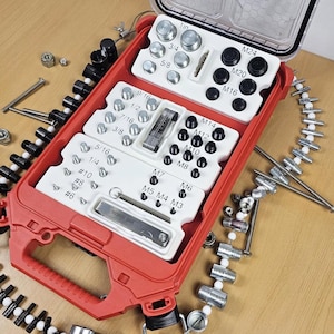 May include: A red plastic case with a white interior containing a variety of metal fasteners. The case has a handle and is open to reveal the fasteners. The fasteners are organized by size and type. The case is on a wooden surface.