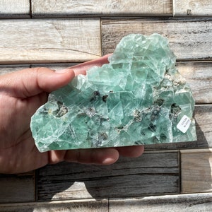 May include: A large, green fluorite crystal with a rough, textured surface. The crystal has a light green colour with darker green inclusions. The crystal is labelled "Fluorite" and "MI-1017".