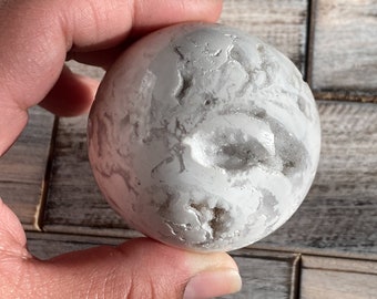 May include: White agate sphere with a natural, rough surface and a crystal-like interior. The sphere is approximately 5 cm in diameter.