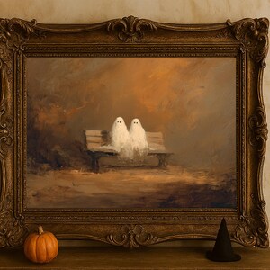 May include: A framed painting depicts two white ghost figures sitting on a park bench. The painting is in a gold ornate frame. A small orange pumpkin and a black witch hat sit in front of the frame, suggesting a Halloween theme.