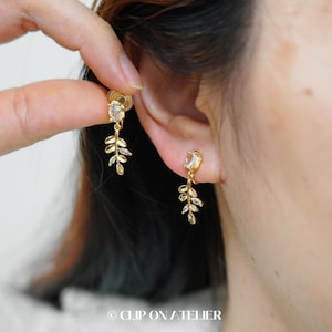 Peut inclure: Boucles d'oreilles en feuille d'or avec des accents de cristal transparent. Les boucles d'oreilles sont de style clip-on.