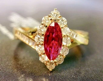 May include: A gold ring with a large, red, marquise-shaped ruby surrounded by a halo of smaller, white diamonds.