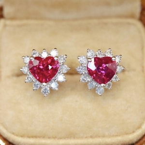 Può includere: Un paio di orecchini a forma di cuore in rubino con un alone di diamanti scintillanti. Gli orecchini sono incastonati in metallo bianco.