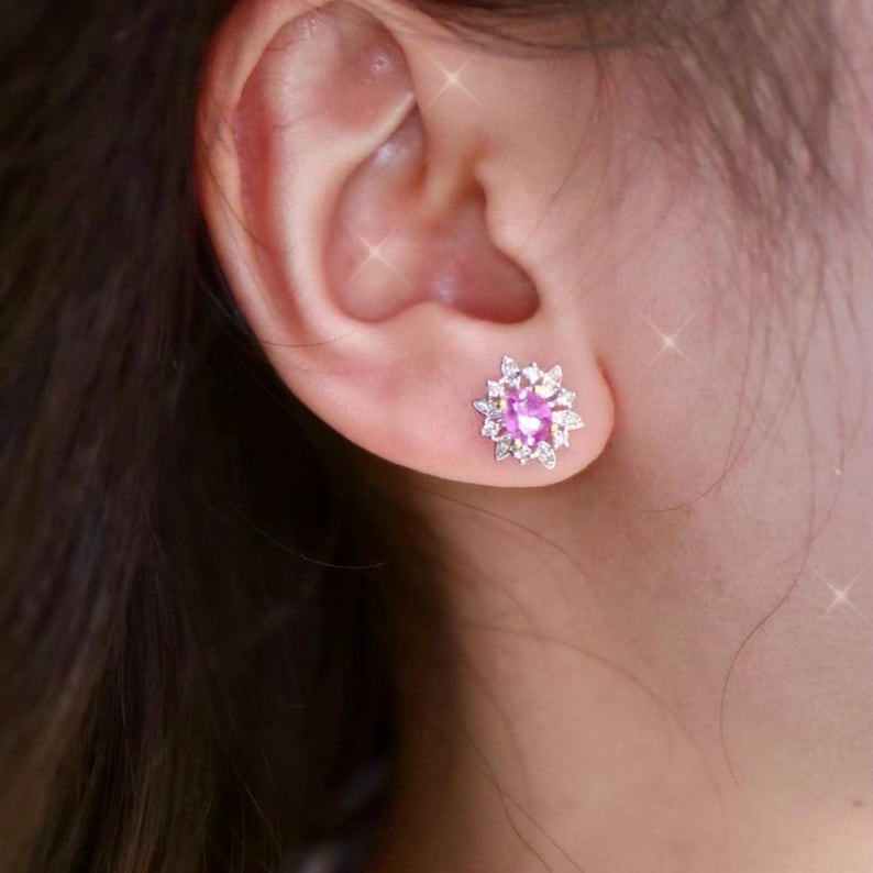 May include: A pair of pink gemstone earrings with a cluster of smaller white gemstones surrounding the center stone.