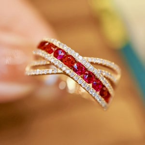 May include: A gold ring with a row of red gemstones and a diamond-encrusted band.