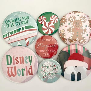 May include: A collection of seven circular pin-back buttons featuring holiday-themed designs. The buttons display illustrations of a monorail with the text OH WHAT FUN IT IS TO RIDE, a peppermint Mickey icon, a gingerbread person, Disney World text, a geodesic dome with lights, and a character wearing a Santa hat.