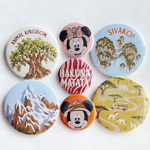 May include: A collection of seven circular pin-back buttons featuring various designs including a tree with the text ANIMAL KINGDOM, a character with a leopard print bow, floating mountains with SIVAKO!, a red zebra print with HAKUNA MATATA, snowy mountains, a character in a safari hat, and a savanna landscape.